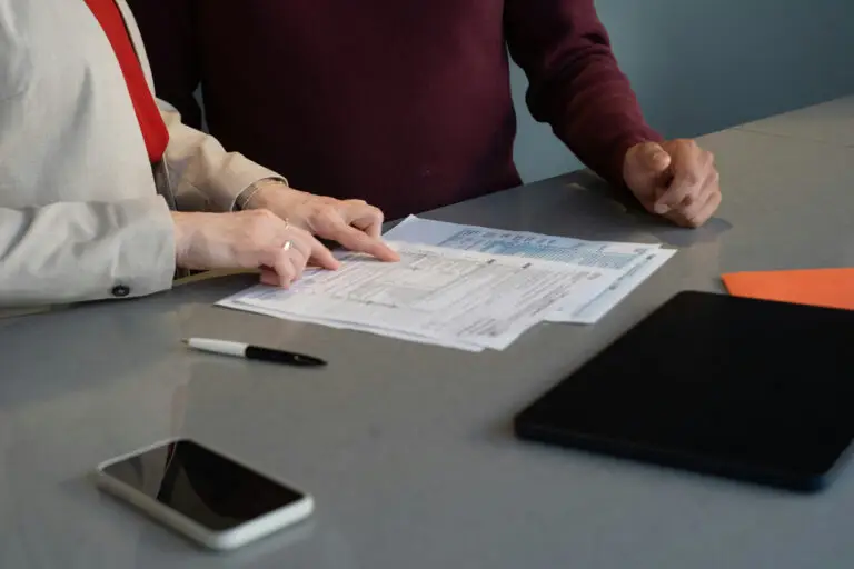 Two people reviewing printed purchase documents at a desk