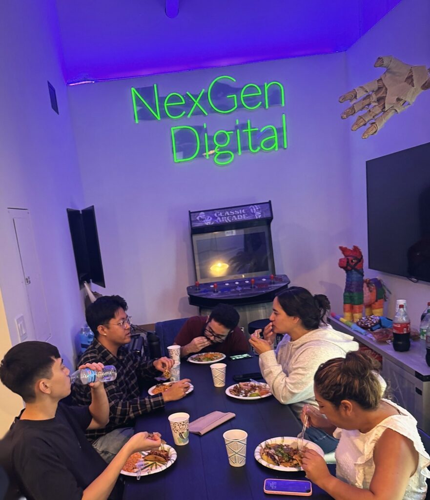 The NexGen Digital team at lunch in the Irvine break room, under the neon sign.